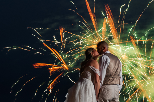 Close up of a couple kissing with the backdrop of orange fireworks after their wedding reception at The Grandview