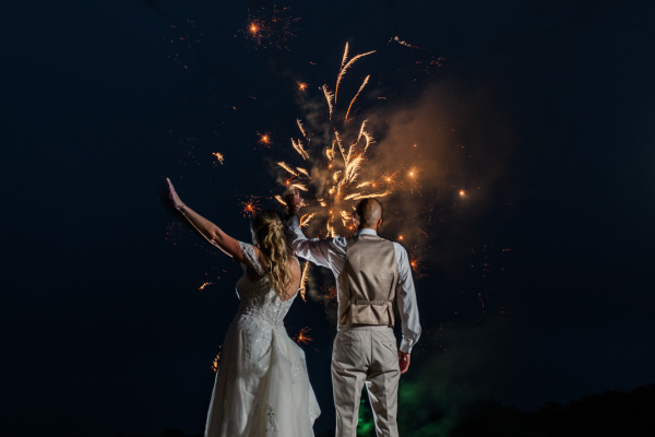 Couple posing in front of fireworks at The Grandview Venue at The Oaks