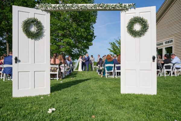 Outdoor wedding ceremony framed by decorative white doors at The Grandview at The Oaks in Somersworth, New Hampshire