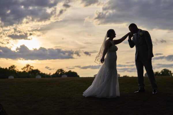 Couple posing on the lawn in front of the sunset at The Grandview