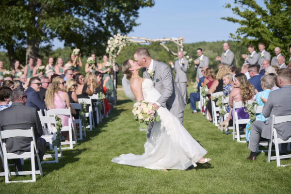 Bride and groom sharing their first kiss during an outdoor wedding ceremony at The Grandview at The Oaks in Somersworth, New Hampshire