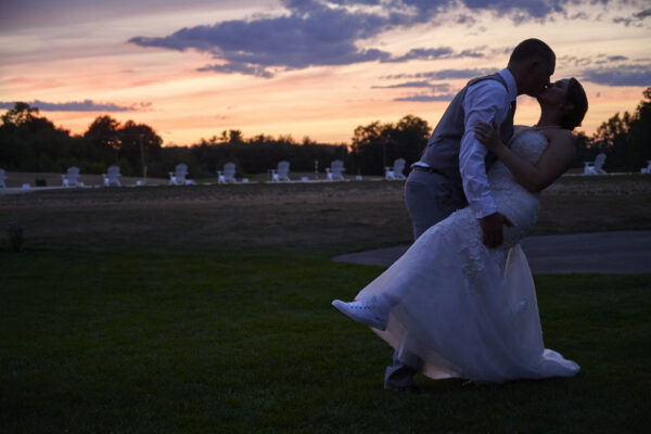 Groom dipping his bride on the lawn before a sunset view, at The Grandview