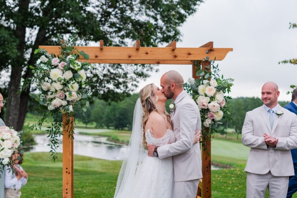 Bride and groom sharing their first kiss during an outdoor wedding ceremony at The Grandview at The Oaks in Somersworth, New Hampshire
