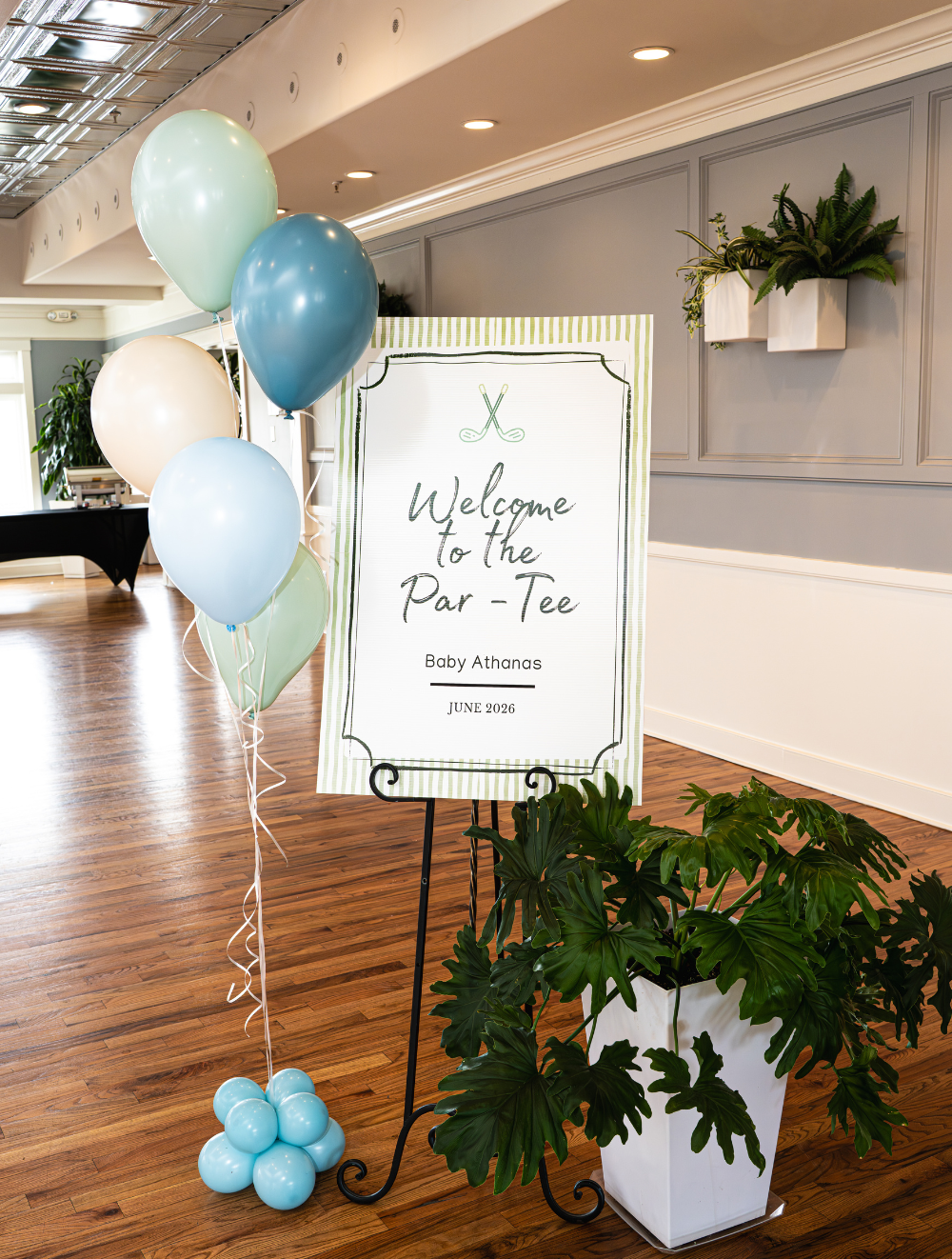 Welcome sign at the entrance of a baby shower event at The Grandview. Blue and green balloons with greenery.