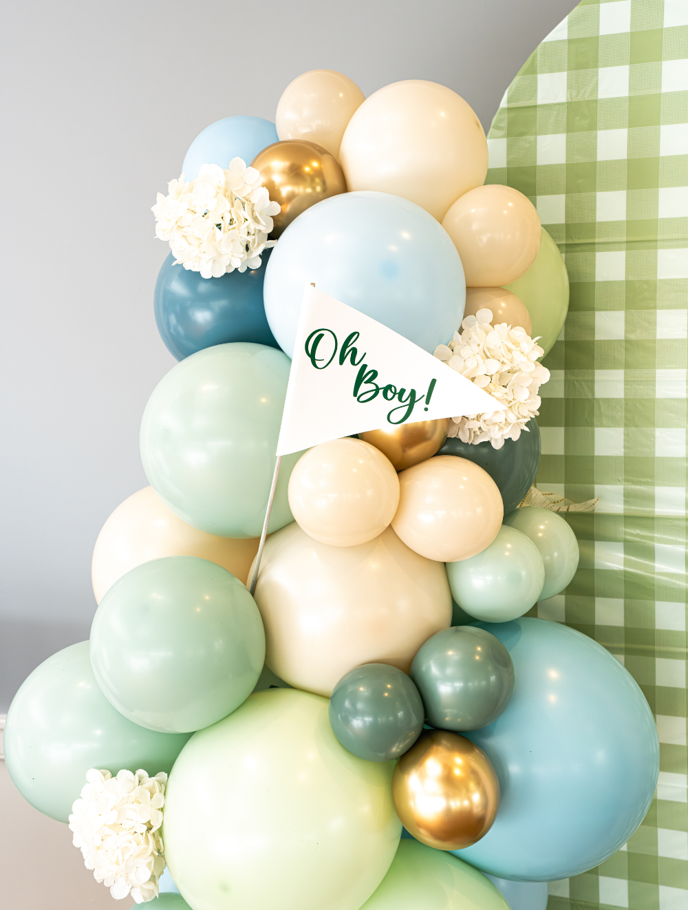 Cream, green, and blue balloon fixture for a baby shower at The Grandview. Balloons are decorated with flowers and a flag with "Oh Boy!".